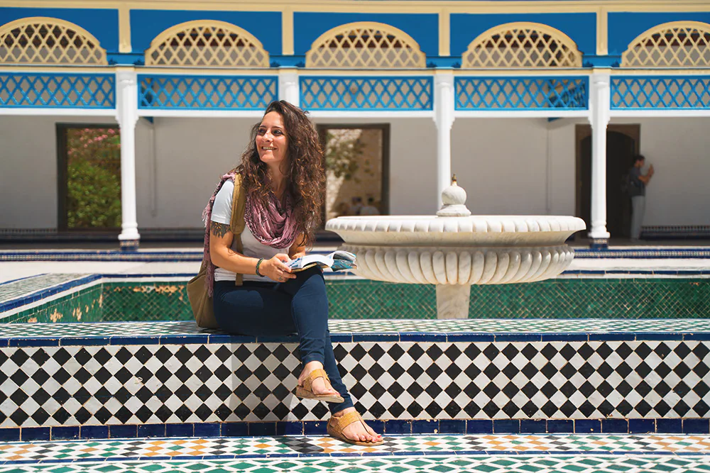 Girl sitting on the edge of the fountain of the Al Bahia palace