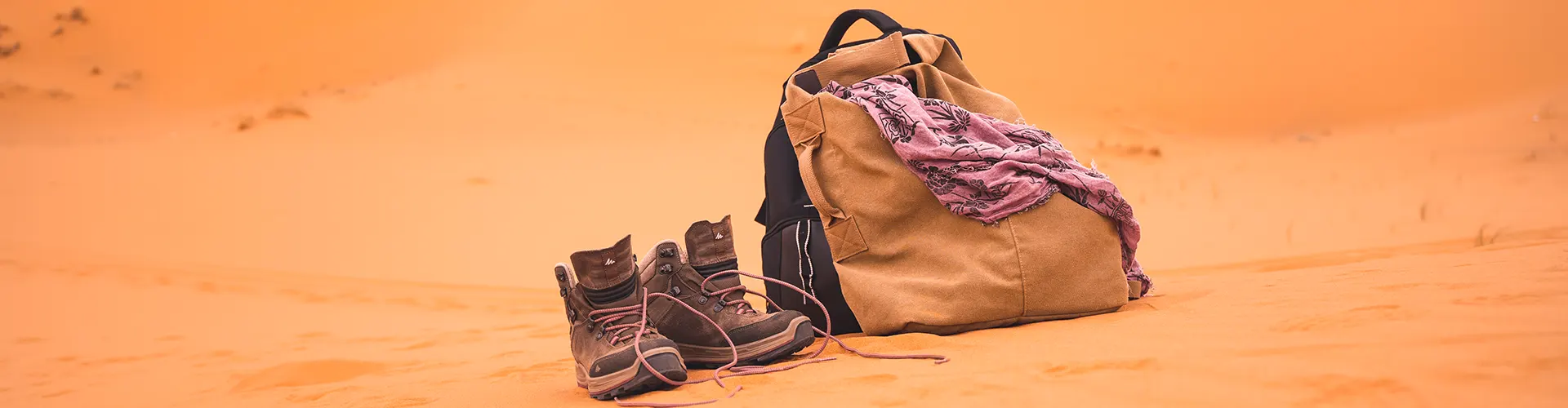 A bag and trekking shoes on the sand of the desert